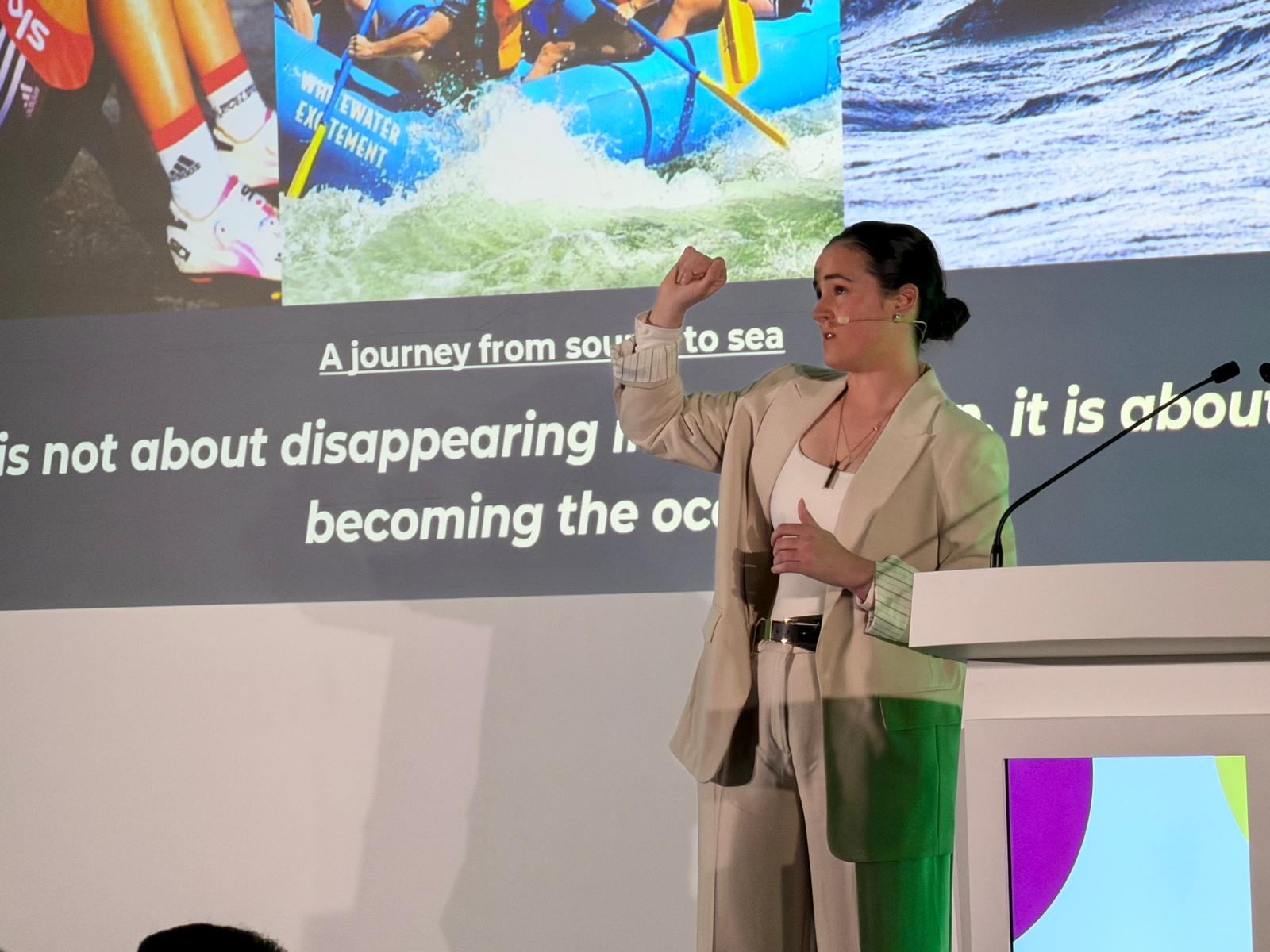 Annasely on stage giving talk to room of people